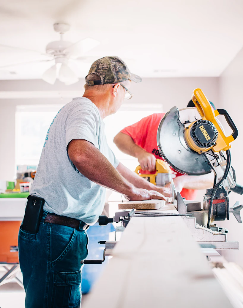 Contractors cutting trim with a miter saw during a home renovation